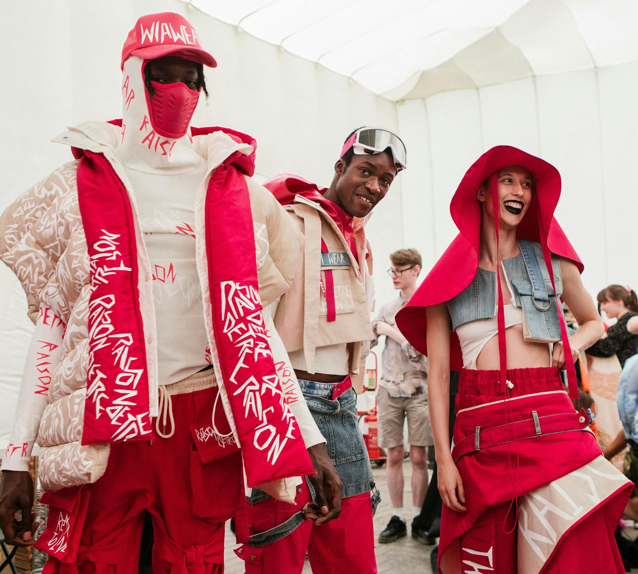 Oliwia Nowotnik's Wia Wear backstage at the London Graduate Fashion Week. The three models are wearing red and white street wear with bold white graphics characteristic of Oliwia's design.