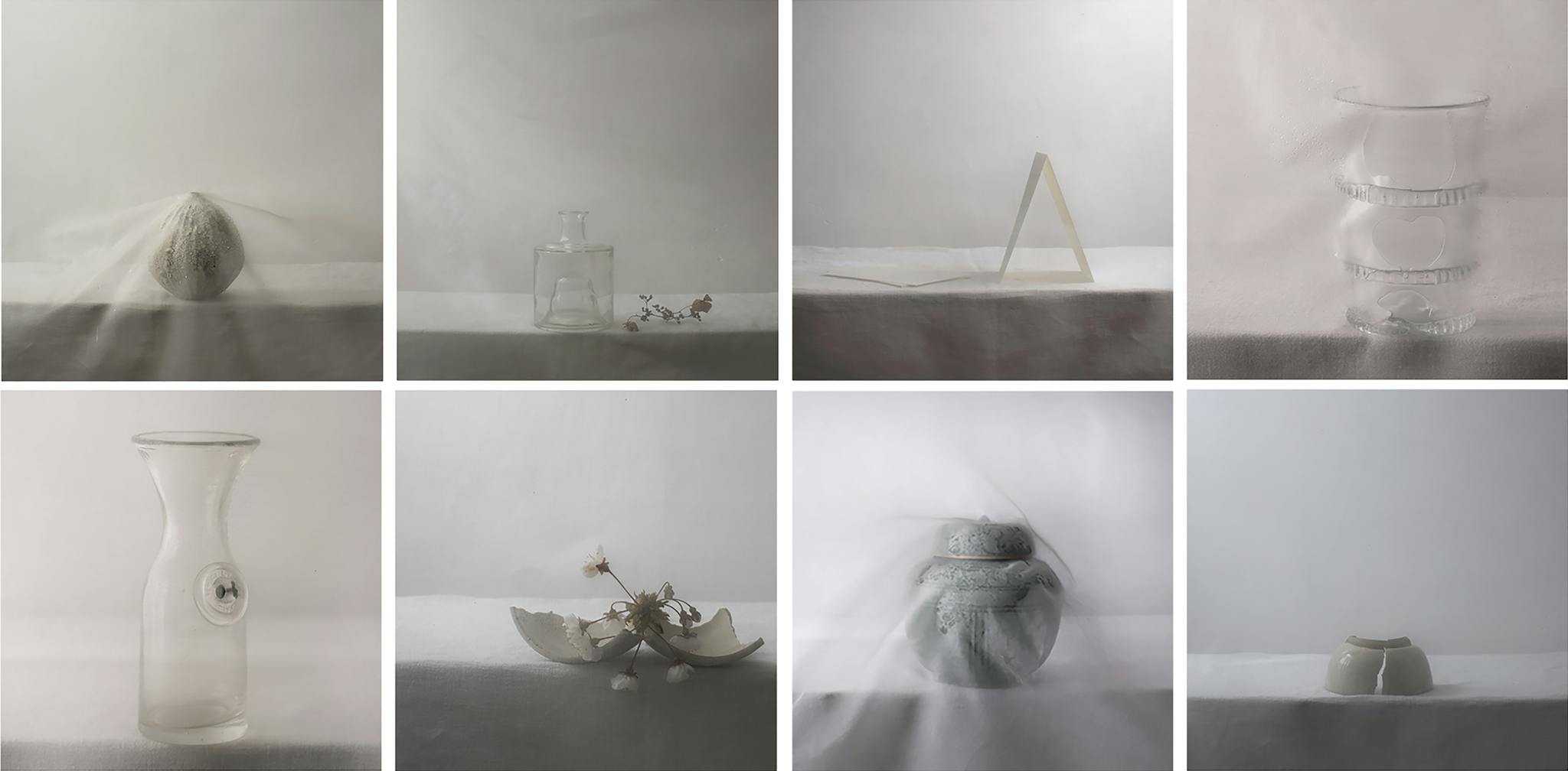 Image shows a series of objects on a surface, shrouded in sheer fabric and with muted tones and lighting