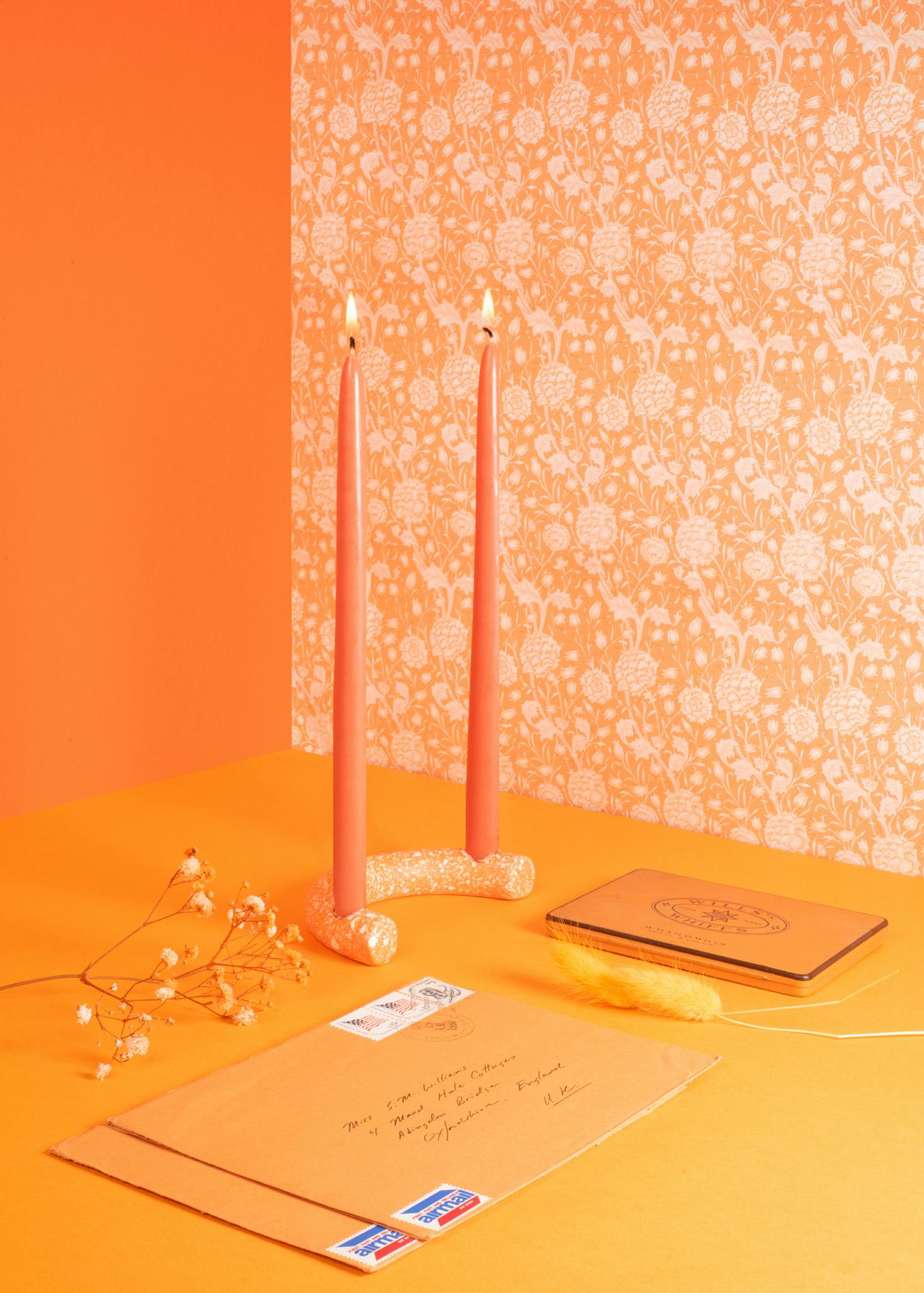 Image shows a room coloured with similar shades of orange with orange objects in the foreground including letters, candles and a feather