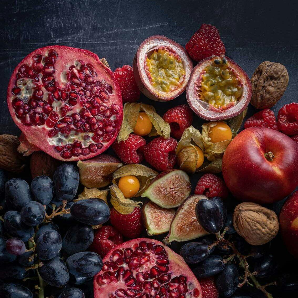 Pomegranates black grapes and figs on a dark background by Emily Read BA Hons Commercial Photography grad from Arts Uni Plym Class of 2022