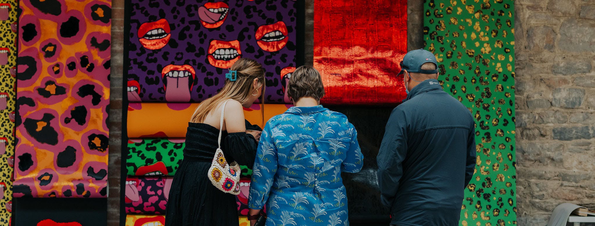 HERO visitors gather around colorful work hung on walls at the Textile Design Summer Show 2022 at Royal William Yard Photo by Luke Frost