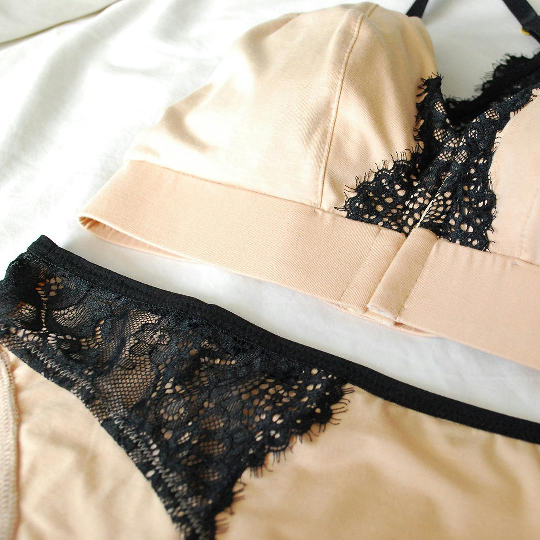 Cream and black lace lingerie laid on a white sheet