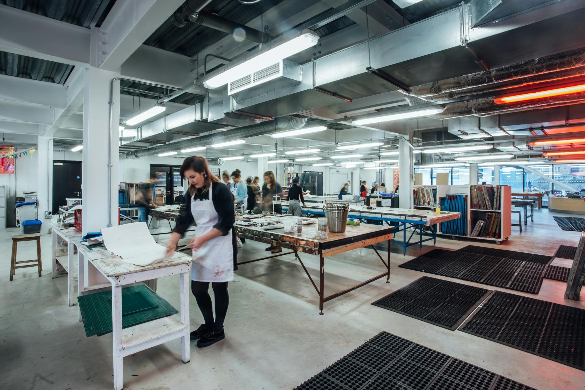 A wide angle shot of Plymouth College of Art's Fabric Lab consisting of work benches, resources and facilities for textiles, printmaking and dyeing