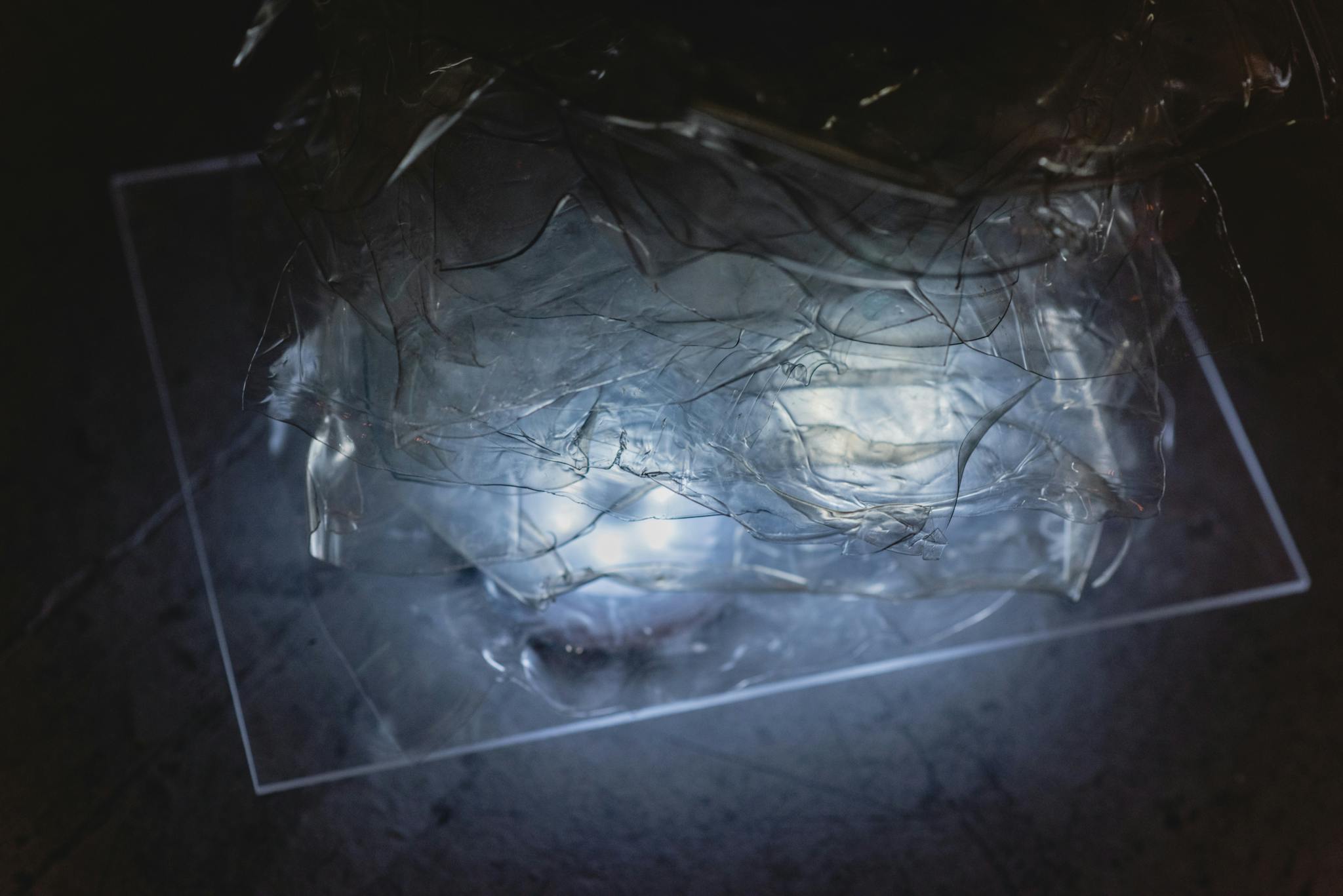 Image shows two lights lighting up a clear piece of perspex and shredded plastic above
