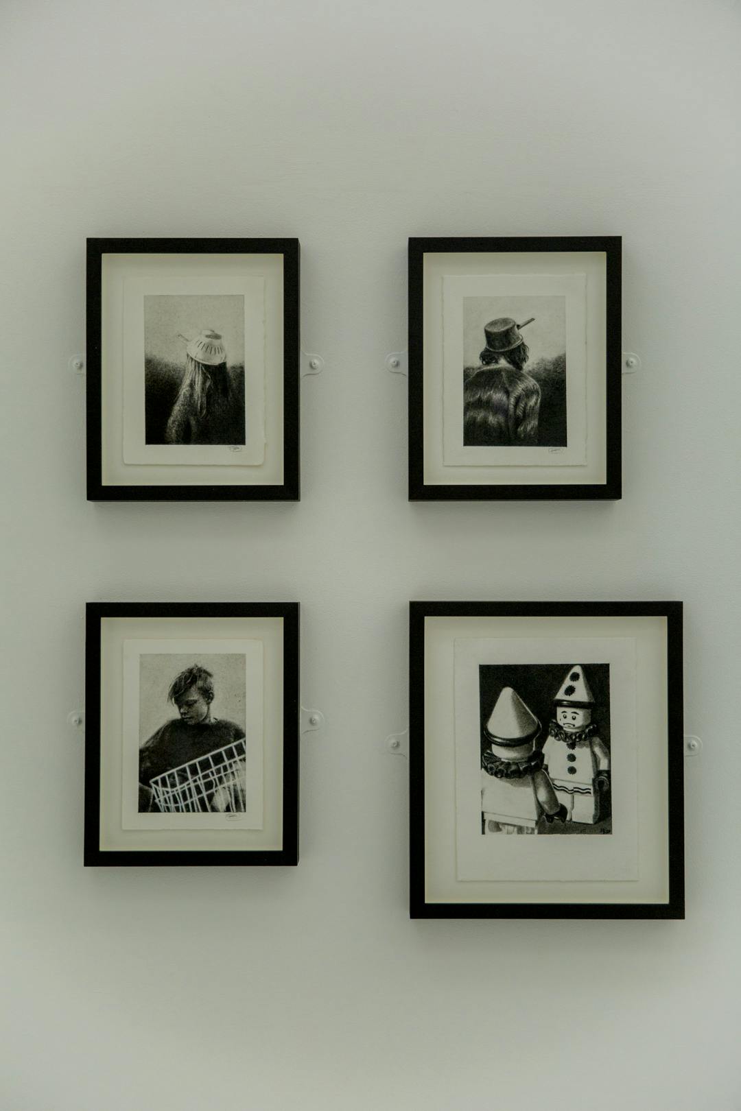 Image shows a collection of Phillip's handdrawn work in thick black frames on a neutral colour wall