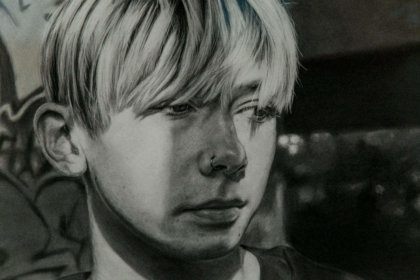 Image shows a black and white hand drawn image of a young boy with light coloured hair looking emotional