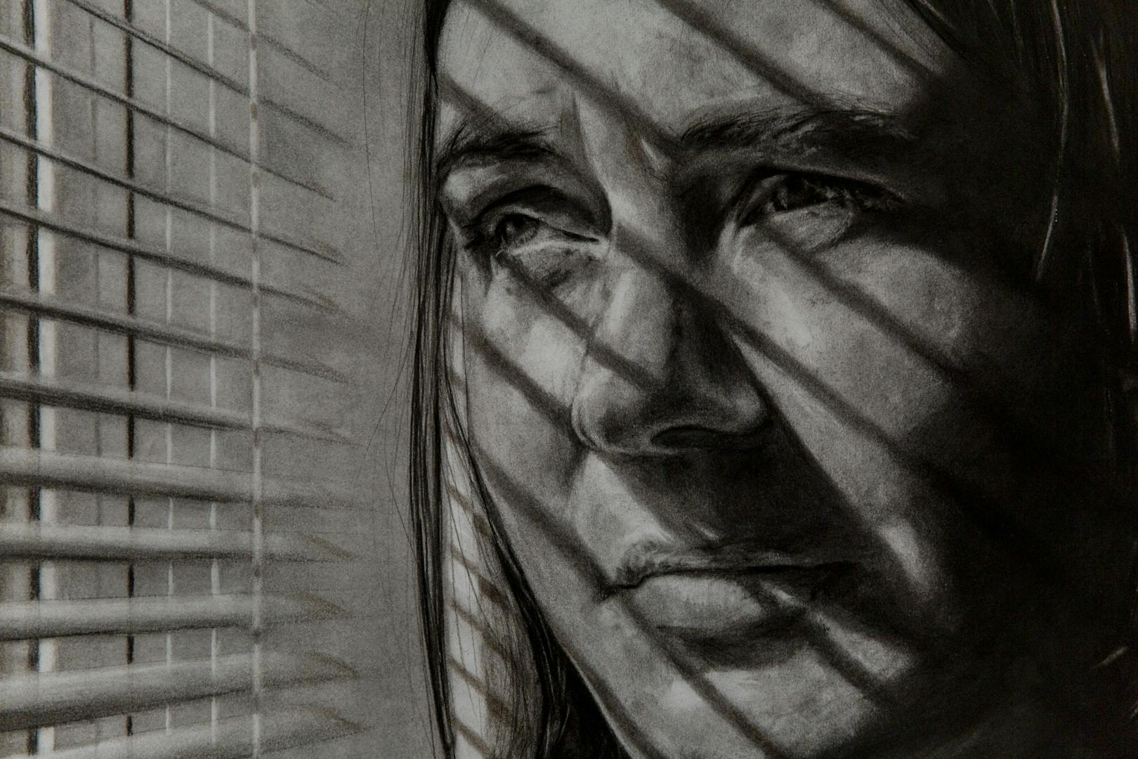 A black and white hand drawn pencil image of a woman staring out of a window with blinds leaving shadows on her face