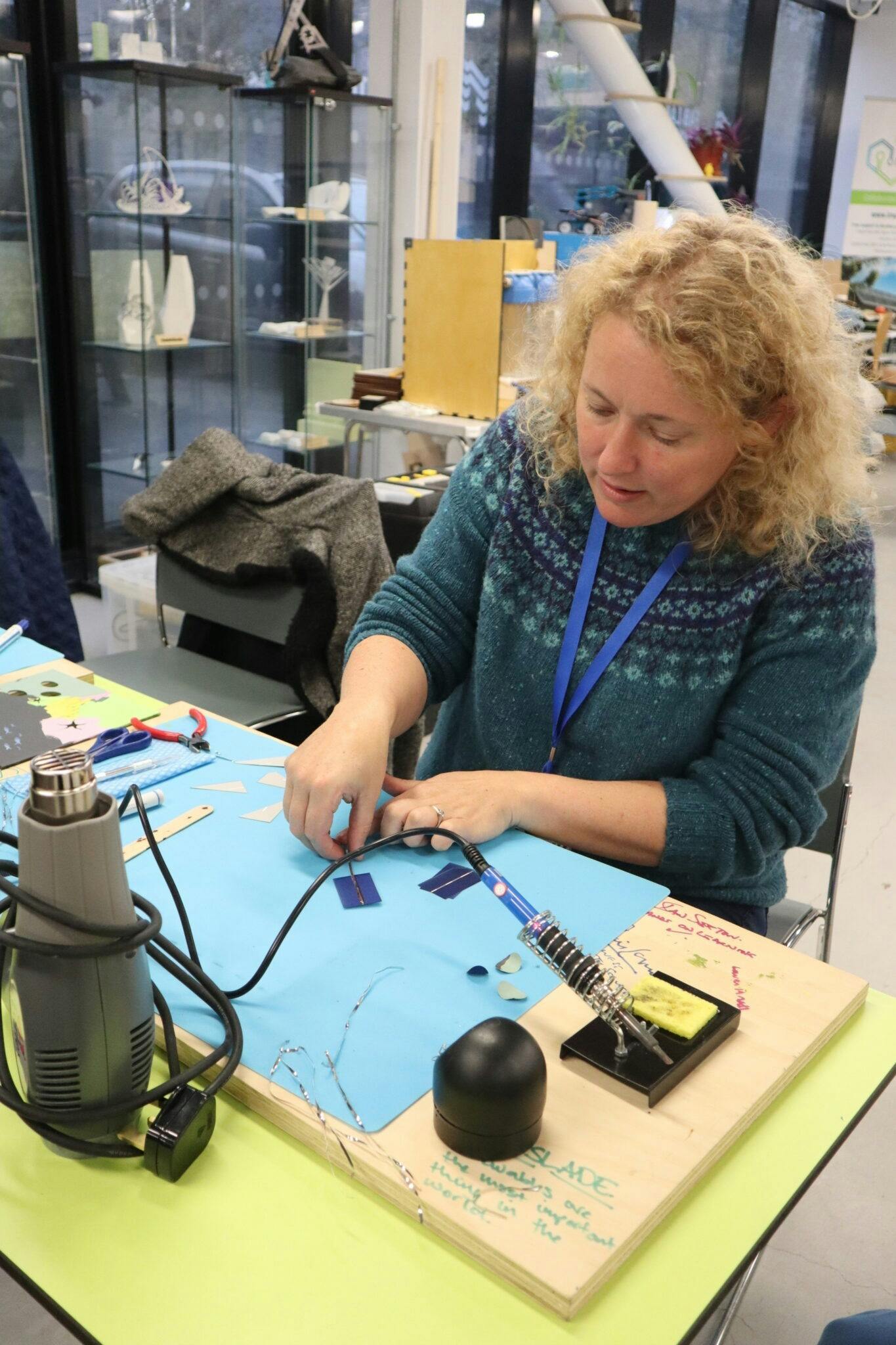 Chloe Uden founder of Art and Energy demonstrating how to solder the solar cells
