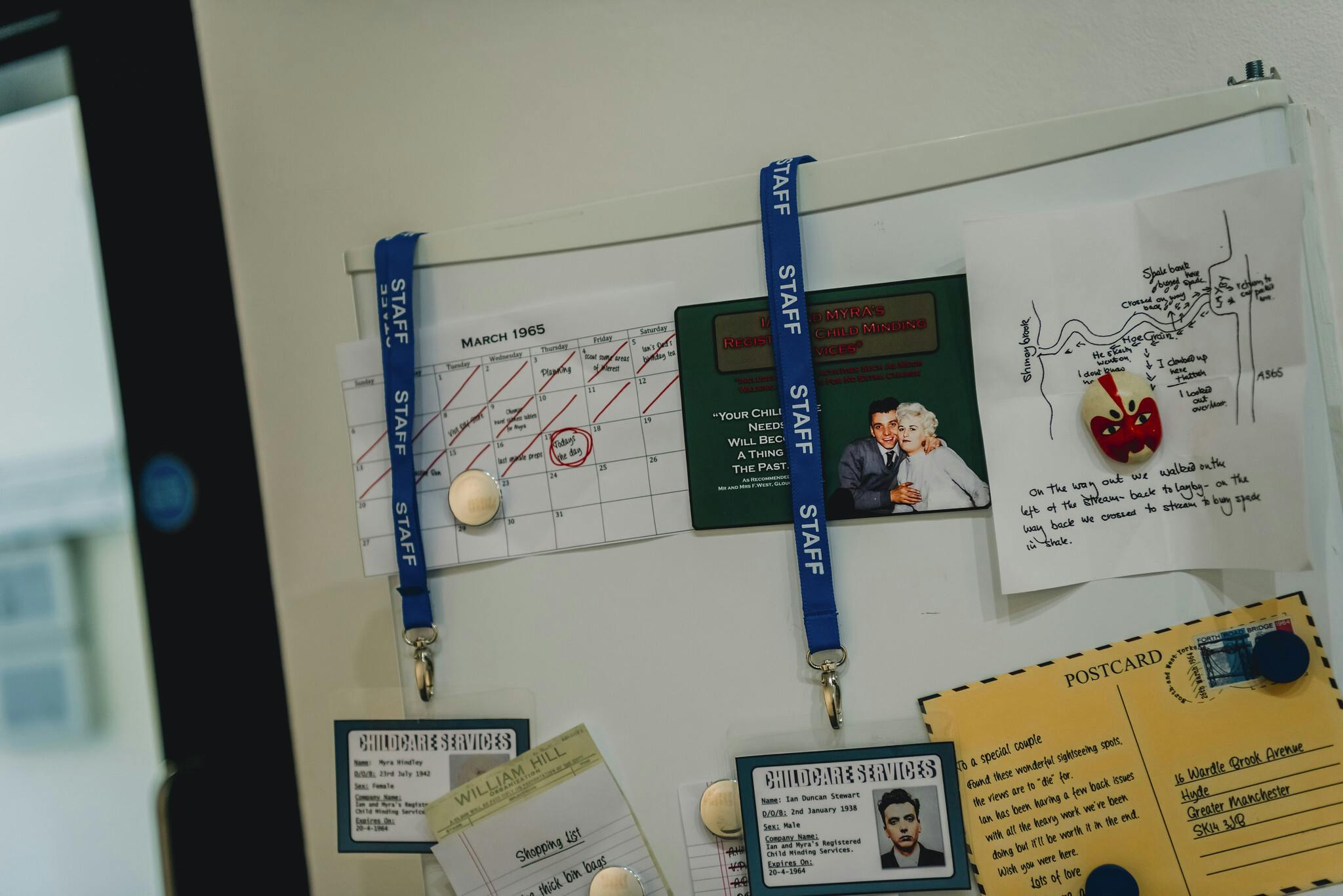 A fridge door shows magnets and hanging staff work cards on lanyards