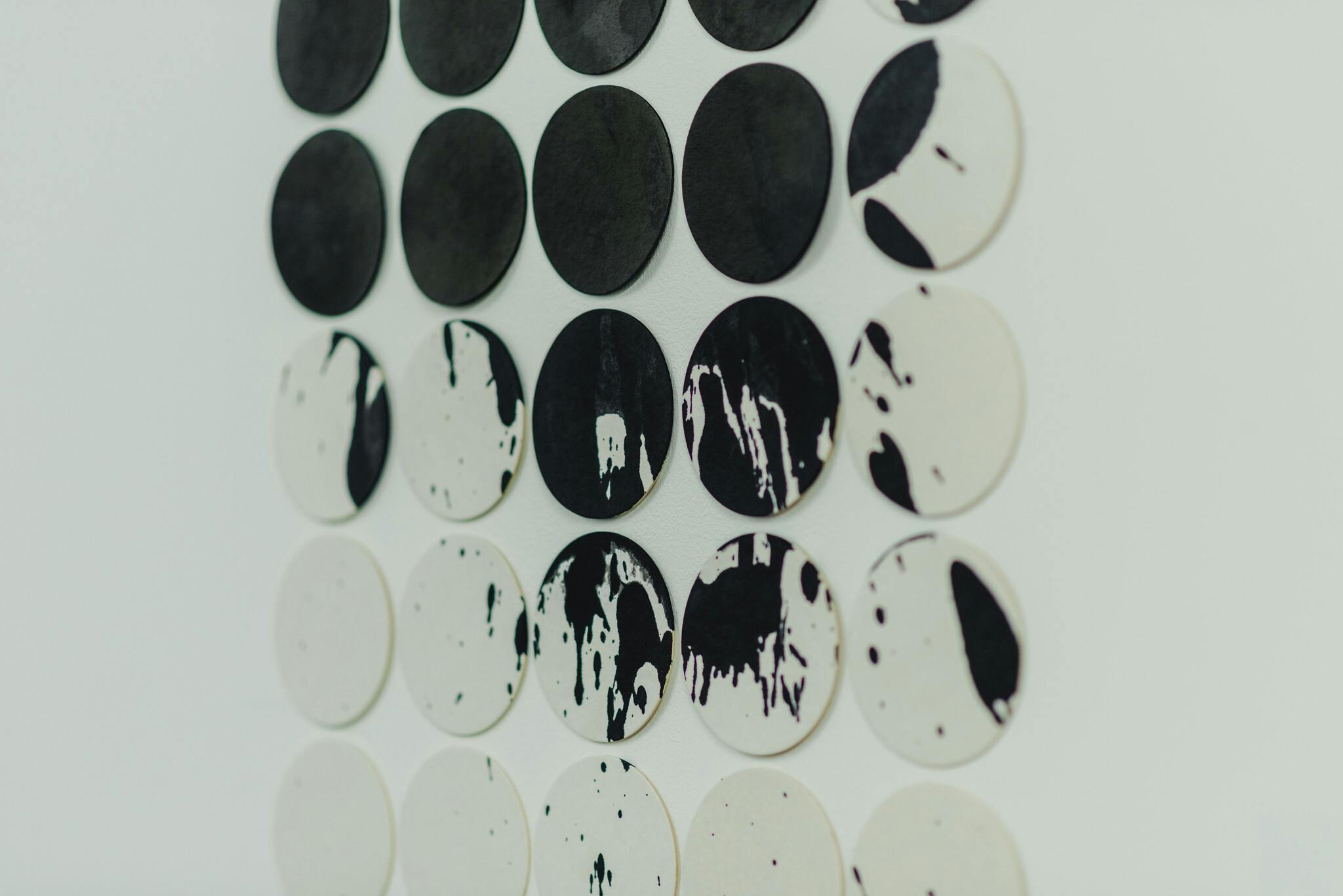Work by Rebecca Alford which shows white paper discs with black paint dripped over them in a gradual pattern