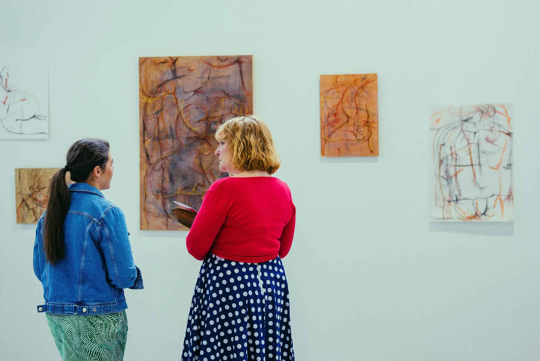 Jo Tyler and Alice Ward speaking to each other in front of Alice's abstract prints at our Summer Shows