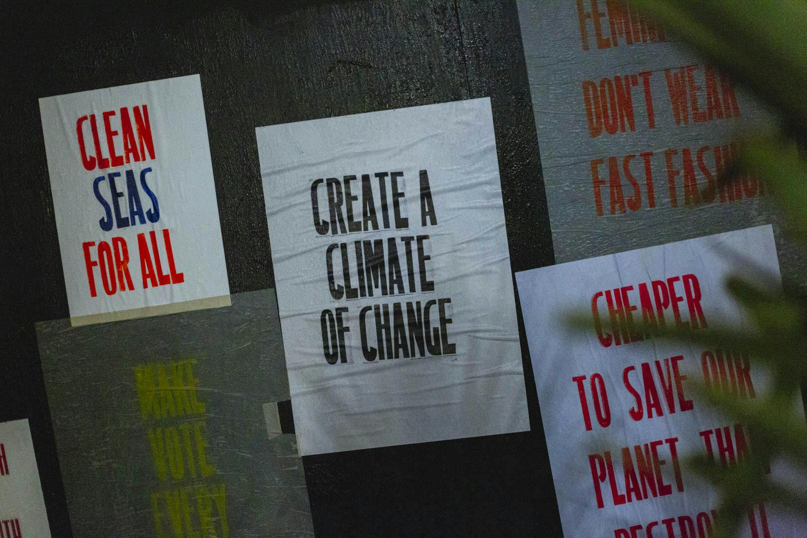 Truth Wall Print at Action Ocean Studios 2022.  There are white posters with coloured type saying "Create a Climate of Change" and "Clean Seas for All"
