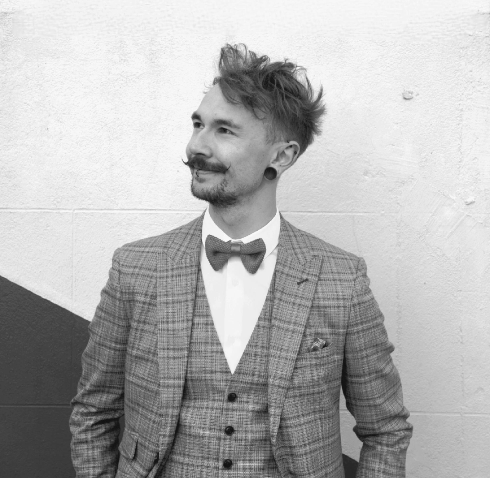 Jack in a waistcoat and suit looking to the side with a moustache and a bowtie