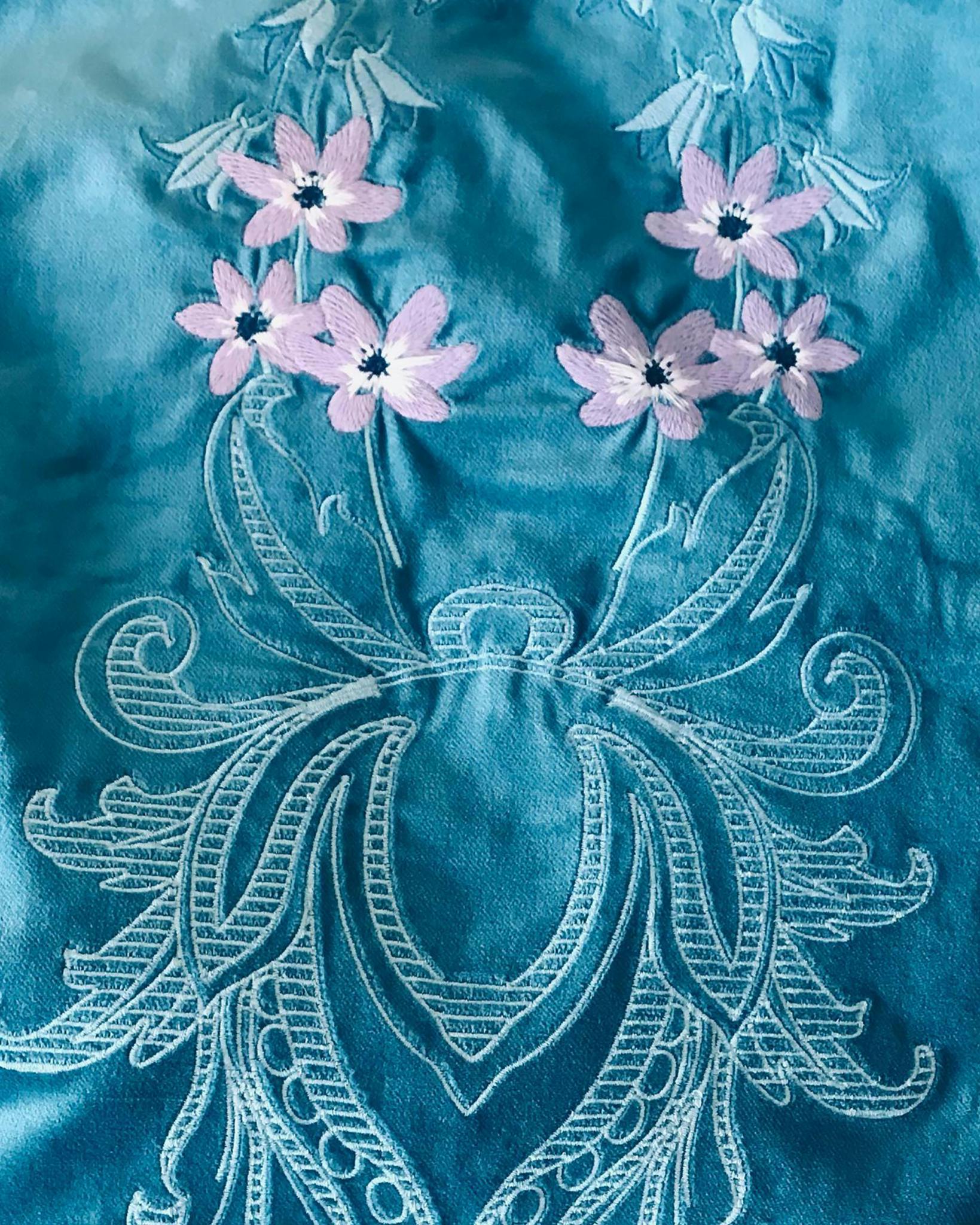 A close up of Katie Furzer's embroidery work featuring blue silk and a pattern designed with thread including pink floral details